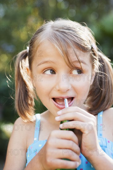 Smiling girl eating candy cigarette in backyard