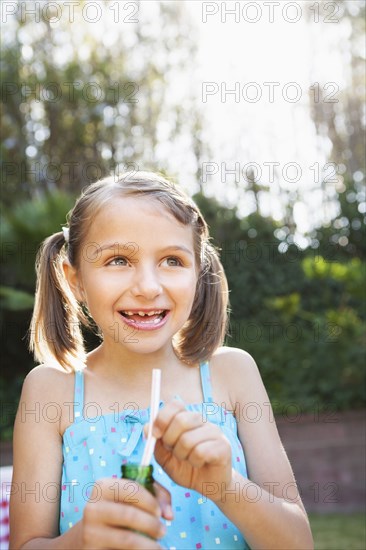 Smiling girl eating candy cigarette in backyard