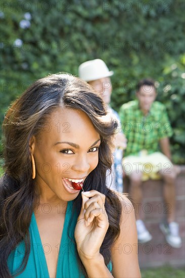 Smiling woman eating cherry in backyard