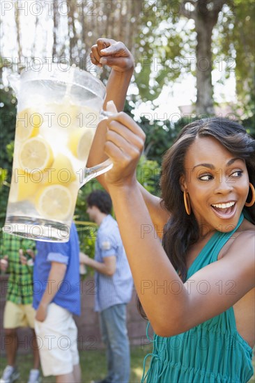 Woman holding pitcher of lemonade at backyard barbecue