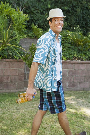 Man carrying cans of beer in backyard