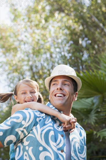 Low angle view of man carrying daughter outdoors