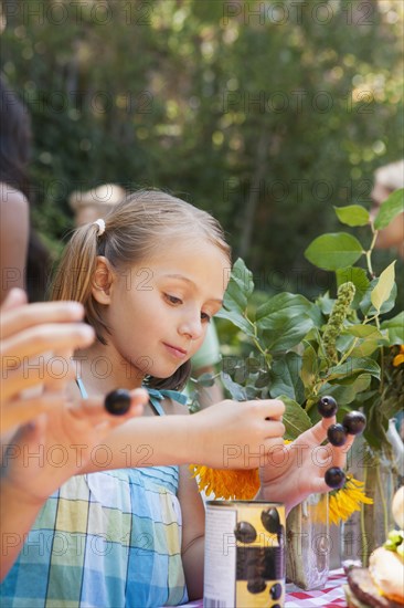 Girl picking flowers and berries in backyard