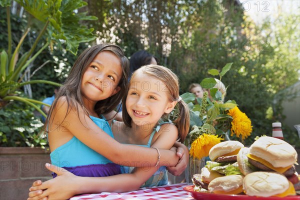 Girls hugging at backyard barbecue