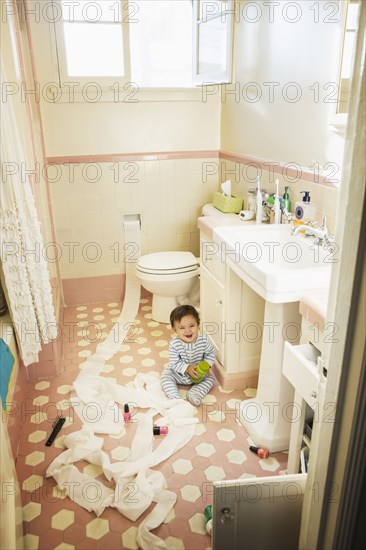 Baby boy playing in messy bathroom