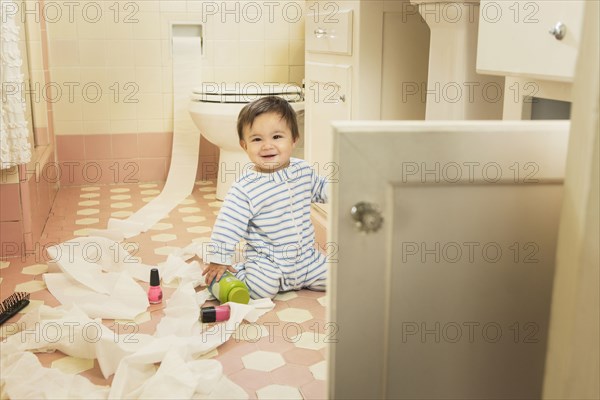 Baby boy playing in messy bathroom