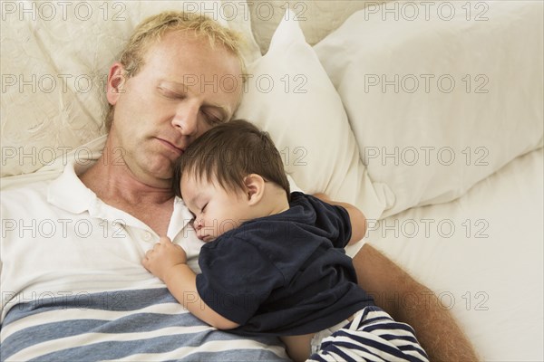 Father and baby son sleeping on bed