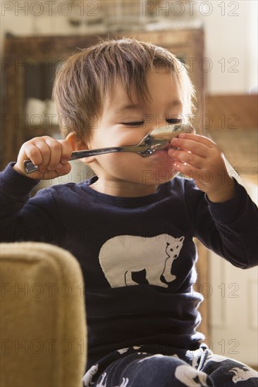 Mixed Race boy holding spoon in mouth