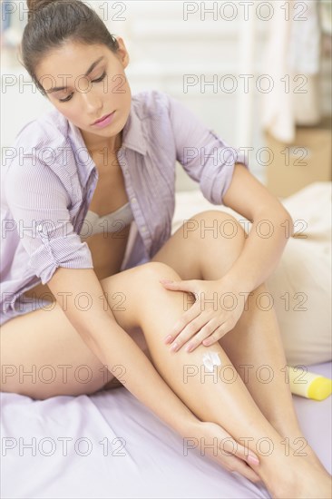 Caucasian woman applying moisturizer to leg