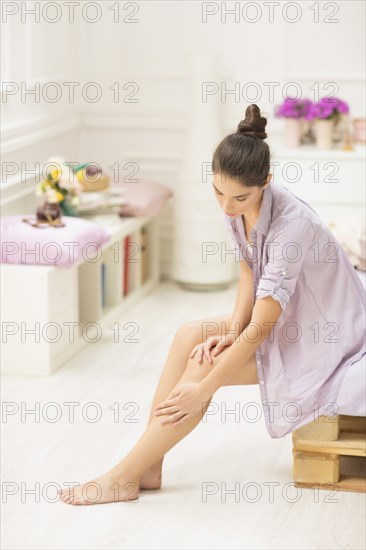 Caucasian woman applying moisturizer to leg