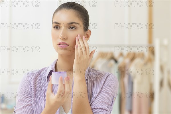 Caucasian woman applying moisturizer to face