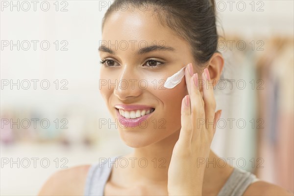 Caucasian woman applying moisturizer to face