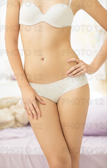 Caucasian woman wearing bra and panties in bedroom