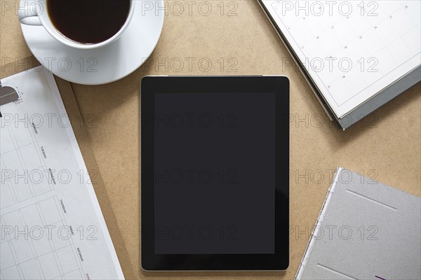 Tablet computer on table with clipboard and coffee