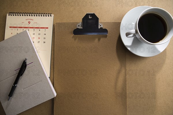 Clipboard and notepad with coffee on table