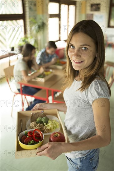 Student carrying lunch tray in school cafeteria