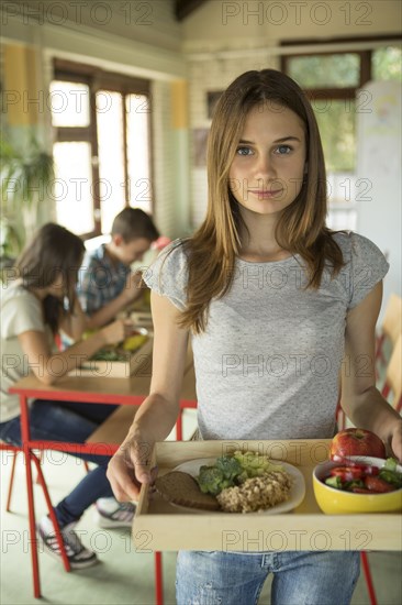 Student carrying lunch tray in school cafeteria