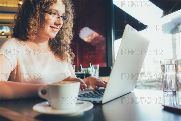 Woman using laptop computer in cafe