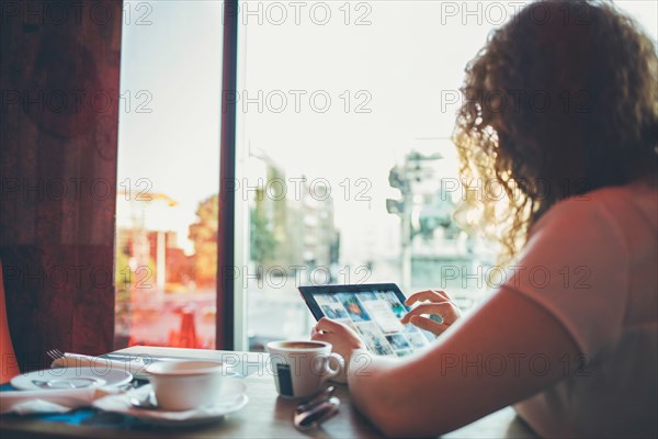 Woman using tablet computer in cafe