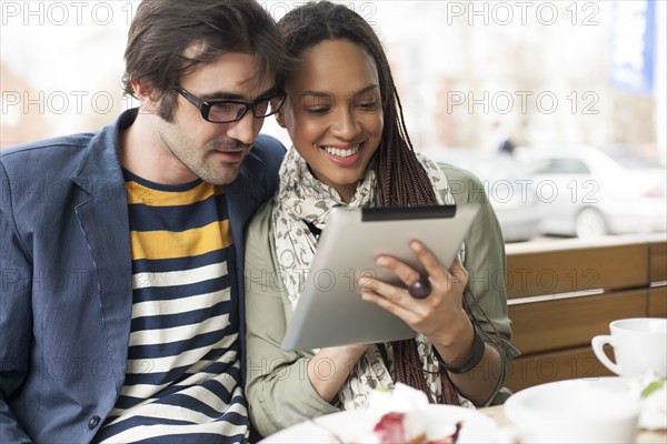 Couple using digital tablet in cafe