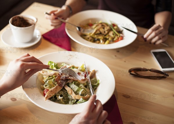 Close up of friends eating salads in cafe