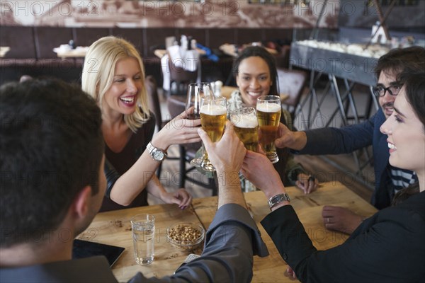 Friends toasting with beer in cafe