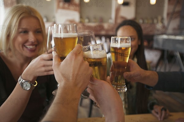 Friends toasting with beer in cafe