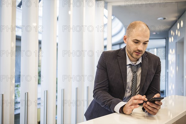 Caucasian businessman using cell phone in office lobby