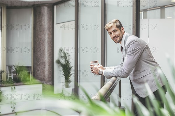 Caucasian businessman drinking coffee on office balcony