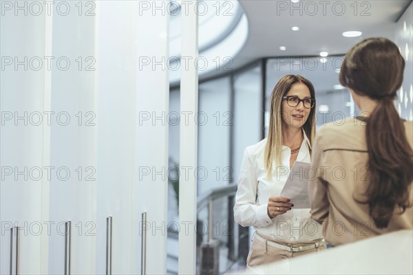 Caucasian businesswoman talking in office corridor