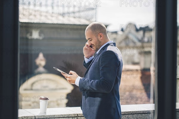 Caucasian businessman talking on cell phone at window