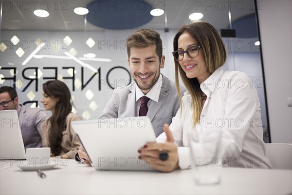 Caucasian business people using digital tablet in office meeting