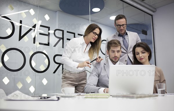 Caucasian business people using laptop in office meeting