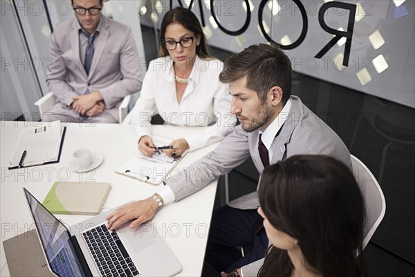 Caucasian business people using laptop in office meeting