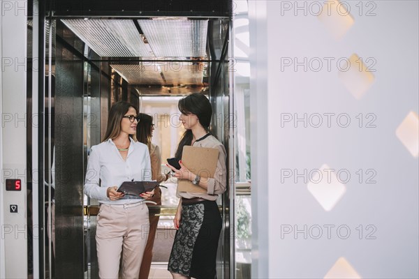 Caucasian businesswomen talking in elevator