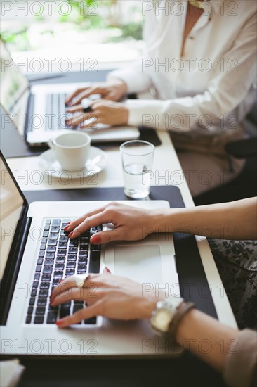 Caucasian businesswomen working at laptops at desk