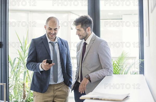 Caucasian businessmen using cell phone in office lobby