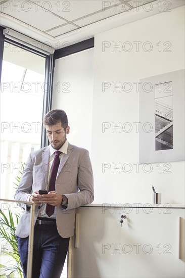 Caucasian businessman using cell phone in office