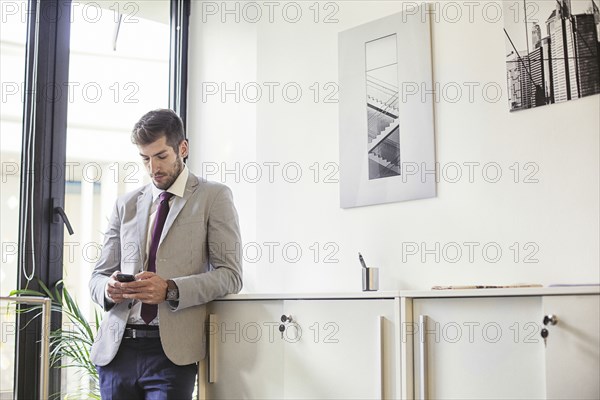 Caucasian businessman using cell phone in office