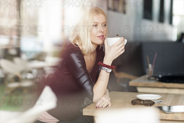 Woman drinking cup of coffee in cafe