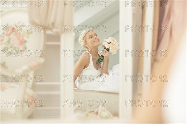 Smiling bride admiring herself in mirror on bed