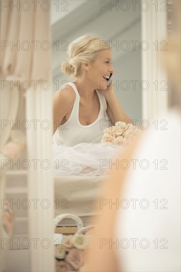 Smiling bride laughing on cell phone in mirror