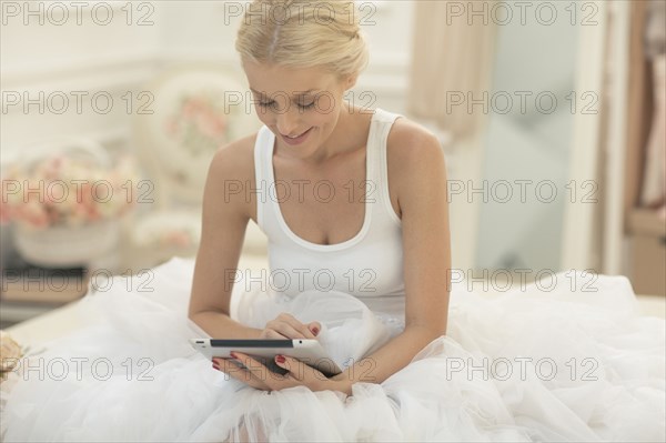 Smiling bride using digital tablet on bed
