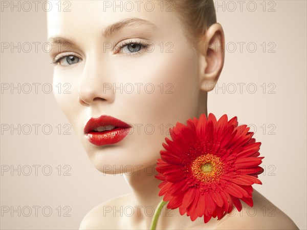 Caucasian woman with red lipstick holding matching flower