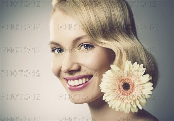 Caucasian woman with pink lipstick wearing white flower