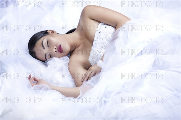 Glamorous woman sleeping in white gown