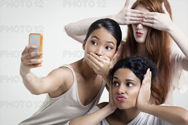 Women posing and taking cell phone selfie