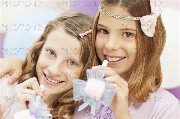 Smiling girls holding noisemakers at party