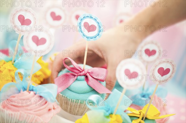 Close up of hand choosing cupcake at birthday party