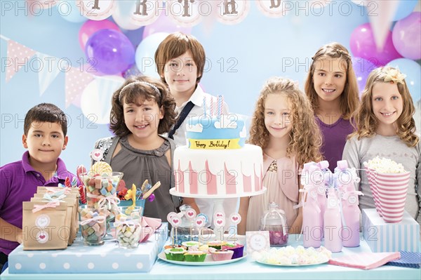 Children smiling near cake and gifts at birthday party